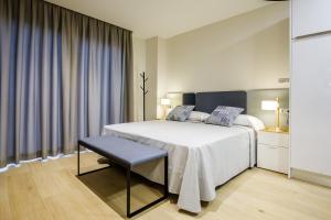 a bedroom with a bed and a chair and curtains at Suites Castellón in Castellón de la Plana
