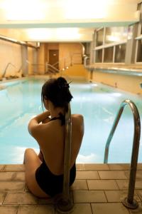 a woman sitting next to a swimming pool at Hotel & Terme Bagni di Lucca in Bagni di Lucca