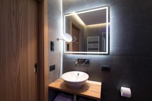 een badkamer met een witte wastafel en een spiegel bij B&B La Tambra - central with Restaurant in Santa Cristina in Val Gardena