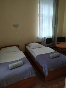 two beds in a room with a window and a table at Dom Turysty in Kostrzyn nad Odrą
