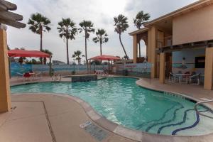 a large swimming pool in a resort with palm trees at Ramada by Wyndham & Suites South Padre Island in South Padre Island