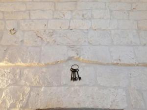 a small key hanging on a white brick wall at Il Casolare nel relax in Ostuni