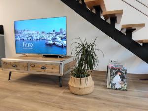 a living room with a television on a wooden table at Casa da Mouraria in Faro