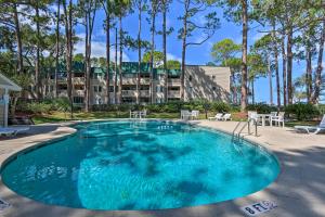 a swimming pool with chairs and a building in the background at Beach and Pool Access Colorful Hilton Head Condo! in Hilton Head Island