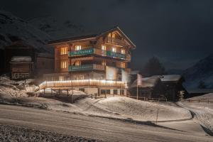 un grande edificio con luci nella neve di notte di Aroleid Lodge a Zermatt
