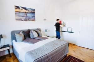a man standing next to a bed in a room at Huge Central Designer Loft with Tyrolean Touch , 160m2 in Innsbruck
