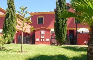 a red house with a fence and palm trees at Olhando um Campo de Golf in Islantilla