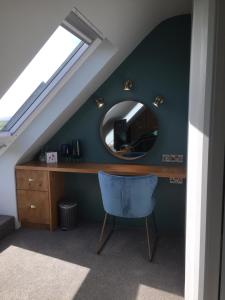 Zimmer mit einem Schreibtisch mit einem Spiegel und einem blauen Stuhl in der Unterkunft Ceol na dTonnta in Doolin