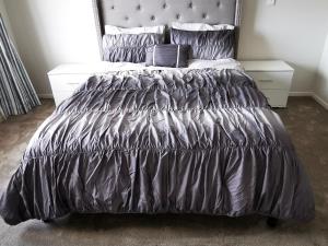 um quarto com uma cama com um edredão cinzento em Flat Bush Private Ensuite em Auckland