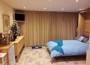 a bedroom with a bed and a christmas tree in it at Sea Moss Cabin in Tywyn