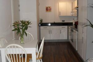 a kitchen with a table with chairs and a vase of flowers at Stylish Wembley Stadium and SSE Arena Apartment, London in London