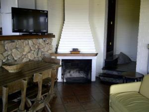 a living room with a fireplace with a flat screen tv at Cabanas Alto Mar in Praia do Rosa