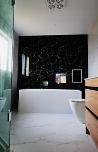a bathroom with a white tub and a black wall at Flat Bush Private Ensuite in Auckland