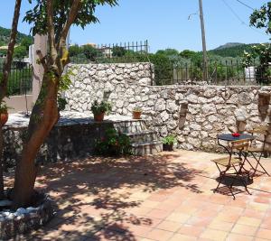 a patio with a stone wall and a table and a tree at House of Garden in Dhráganon