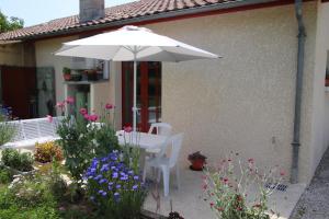 LE Gîte DE LA GRANGE DE BROUSTIC في Lahosse: طاولة بيضاء مع مظلة وبعض الزهور