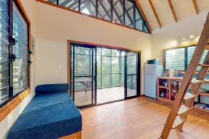 a living room with a blue couch and windows at Inn The Trees Cabañas in Placencia Village