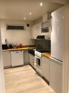 cocina con electrodomésticos blancos y suelo de madera en Leilighet, en Tromsø