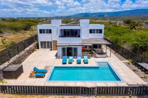 a villa with a swimming pool in front of a house at Turtles Nest Villa in Treasure Beach