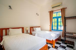 two beds in a room with a window at Vida Loca Sunset Beach Resort in Phu Quoc
