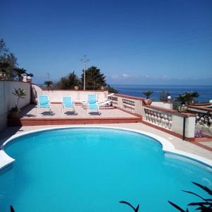 basen z 2 niebieskimi krzesłami i oceanem w obiekcie Villa Teresa w mieście Trappeto