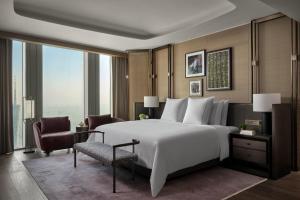 a bedroom with a large white bed and a chair at Rosewood Guangzhou in Guangzhou