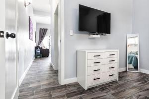 a hallway with a white dresser and a television on a wall at Mangata Villas Adults Only in San Pedro