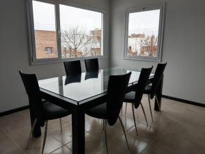 a dining room with a glass table and black chairs at Amoblados Cipolletti in Cipolletti