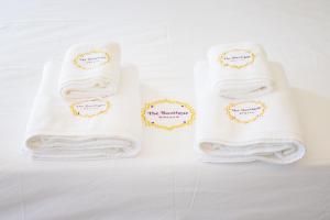 three white towels with gold stickers on them at The Boutique Khanom in Khanom