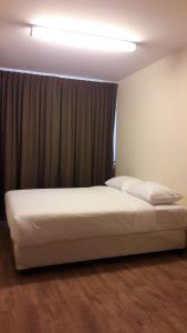 a white bed in a room with a window at The Blooms Residence in Bangkok