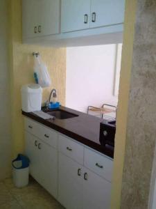 cocina con armarios blancos, fregadero y ventana en Condomínio Cabo Frio en Cabo Frío