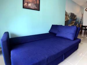 ein blaues Sofa in einem Zimmer mit blauer Wand in der Unterkunft Amerin Mall & Suites in Seri Kembangan