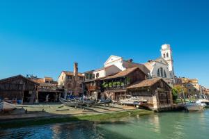 a group of buildings next to a river with boats at La casa del pescatore: a lovely escape in Venice!! in Venice