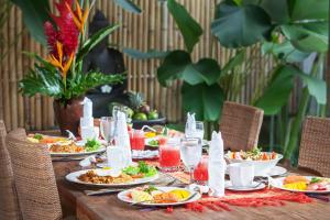 a long table with plates of food and drinks at Villa Damar Canggu by Nagisa Bali in Canggu