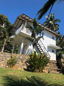 une maison blanche avec un escalier au-dessus d'un mur en pierre dans l'établissement Hiru Villa Tangalle, à Tangalle