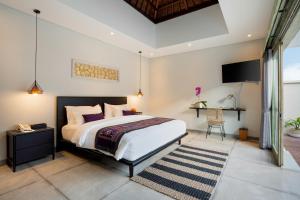 a bedroom with a bed and a desk and a television at La Numa Villas Canggu in Canggu +59 photos