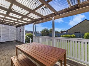a wooden bench on a deck with a pergola at Driftwood House in Port Fairy