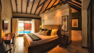 a bedroom with a bed with a desk and a window at Warwick Le Lagon Resort & Spa, Vanuatu in Port Vila
