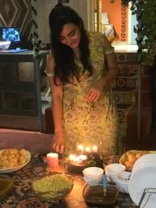 una mujer parada frente a una mesa con un pastel con velas en NAMASTEY MUMBAI BACKPACKERS en Bombay