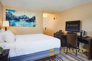 a hotel room with a bed and a desk with a television at Grande Rockies Resort-Bellstar Hotels & Resorts in Canmore
