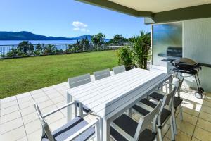 a white table and chairs on a patio with a grill at Hamilton Island Holiday Homes in Hamilton Island