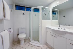 a bathroom with a shower and a toilet and a sink at Hamilton Island Holiday Homes in Hamilton Island