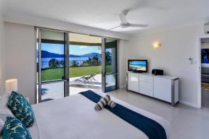 a bedroom with a large white bed and a television at Hamilton Island Holiday Homes in Hamilton Island
