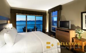 een slaapkamer met een bed, een televisie en een balkon bij The Beach Club Resort — Bellstar Hotels & Resorts in Parksville