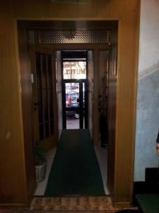 un corridoio con un tappeto verde di fronte a una porta di Hotel Acapulco a Milano