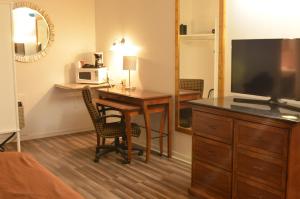 a hotel room with a desk with a microwave and a television at The Oak Motel in La Grange