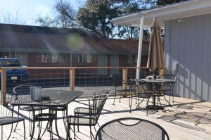 un patio con mesas, sillas y una sombrilla en The Oak Motel, en La Grange