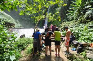un grupo de personas de pie en un sendero cerca de una cascada en Meme Surung Guesthouse, en Munduk