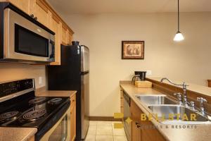 a kitchen with a black refrigerator and a sink at Palliser Lodge — Bellstar Hotels & Resorts in Golden