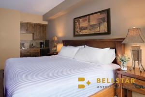 een slaapkamer met een groot bed met witte lakens bij Glacier Mountaineer Lodge in Golden