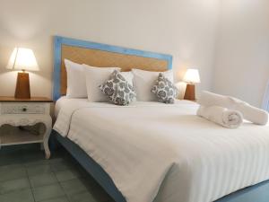 a bedroom with a large white bed with pillows at Jukung Guest House in Sanur
